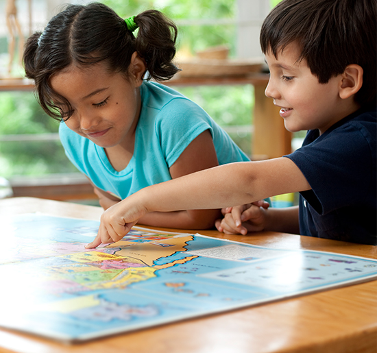一个小男孩和一个小女孩看着桌子上的地图