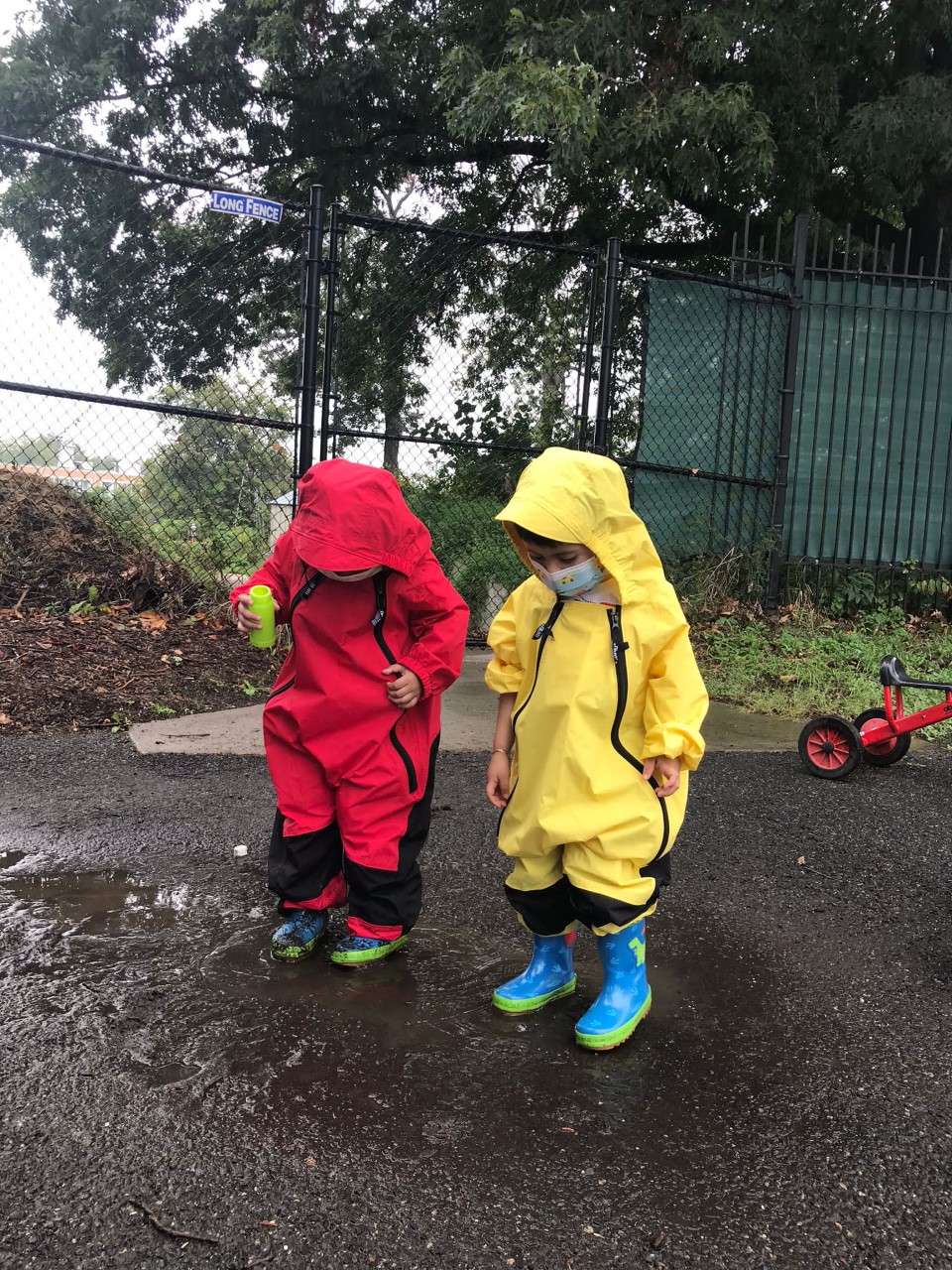 两个穿着防雨服的孩子在水坑里探索