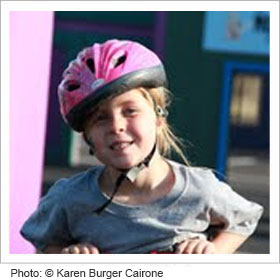 小女孩戴着头盔骑自行车