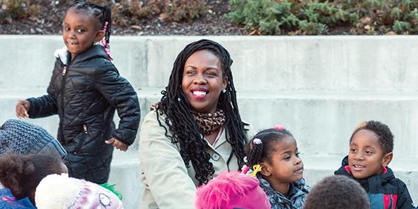 非裔美国老师和幼儿园学生坐在外面
