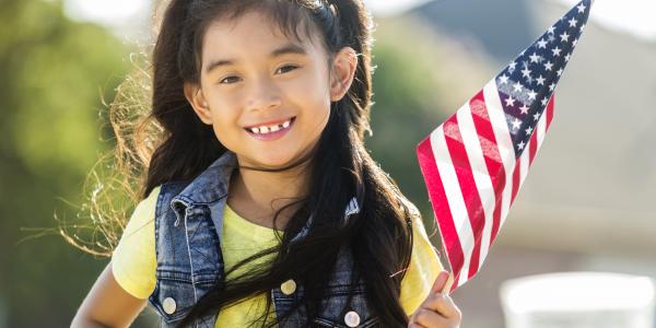 一个学龄前的小女孩举着一面美国国旗