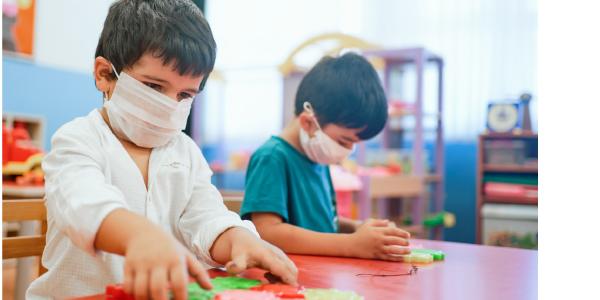 两个孩子戴着防护面具在教室里玩耍。