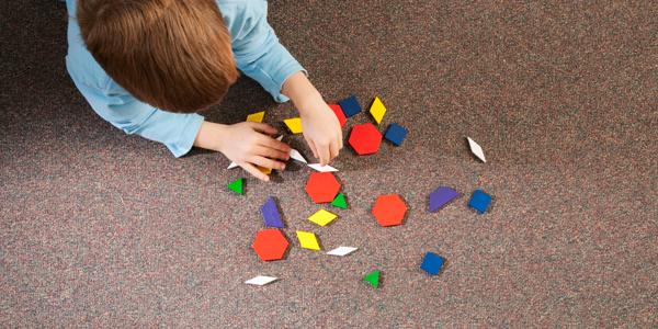 一个学龄前儿童在地毯上玩几何图形