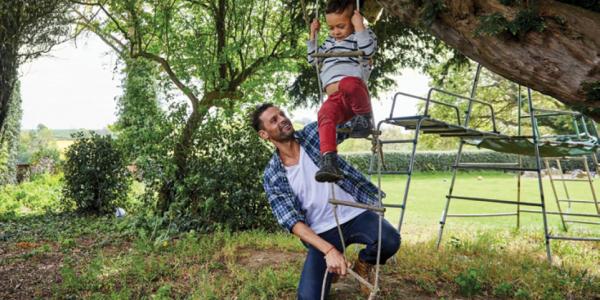一位父亲带着孩子在外面的绳梯上玩耍