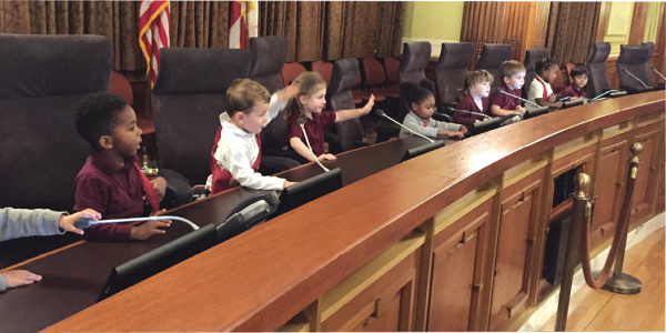 市政厅的一群学龄前儿童坐在桌子上。