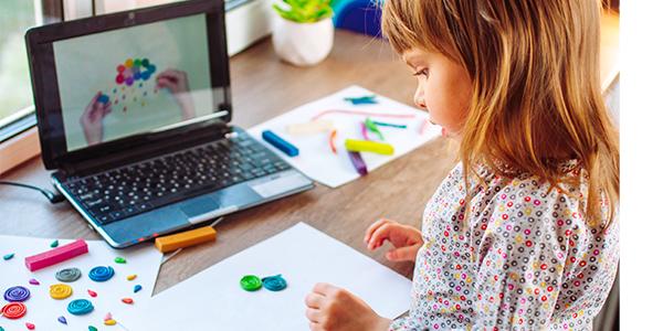 Una niña haciendo arte frente a Una computadora。