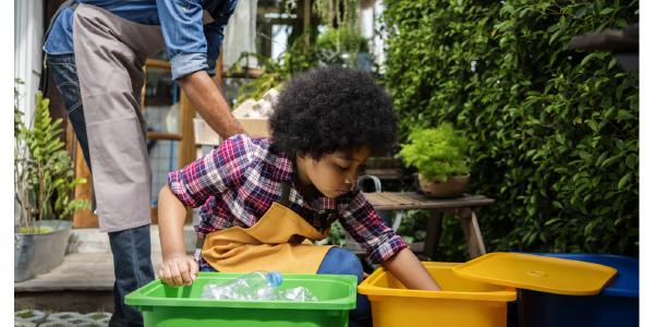 一个年幼的孩子把回收物分类到桶里。