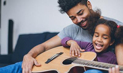 父亲和女儿在沙发上弹吉他