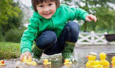 小孩在外面的水坑里玩橡皮鸭