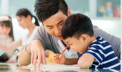学龄前儿童和父亲在书桌前写作