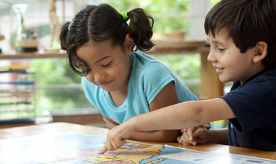 一个年轻的男孩和女孩指着桌子上的地图在教室里