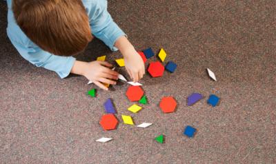 一个学龄前儿童在地毯上玩几何图形