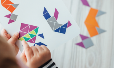 一个小孩在一张纸上复制各种几何形状的设计。