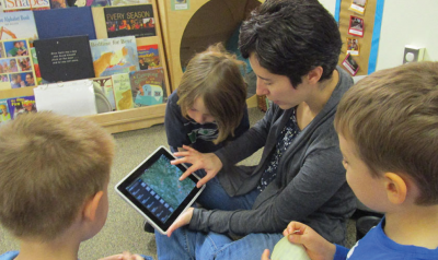 一位老师在给孩子们展示iPad上的游戏