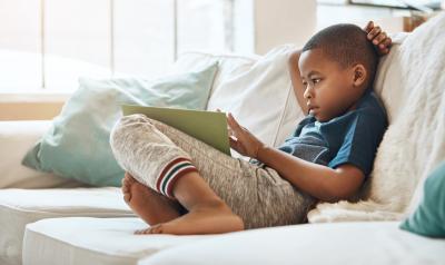 学前班的小男孩坐在沙发上看书