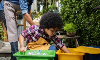 一个年幼的孩子把回收物分类到桶里。