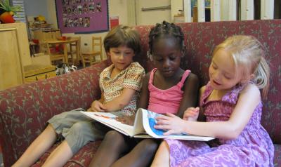 三个学龄前儿童在教室里坐在椅子上看书