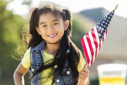 一个学龄前的小女孩举着一面美国国旗