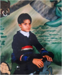 作者三年级时的照片。画的是一个男孩坐在画好的背景前。