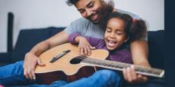 父亲和女儿在沙发上弹吉他