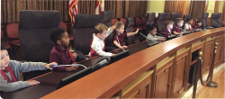 一群学龄前儿童坐在市政厅的桌子前。